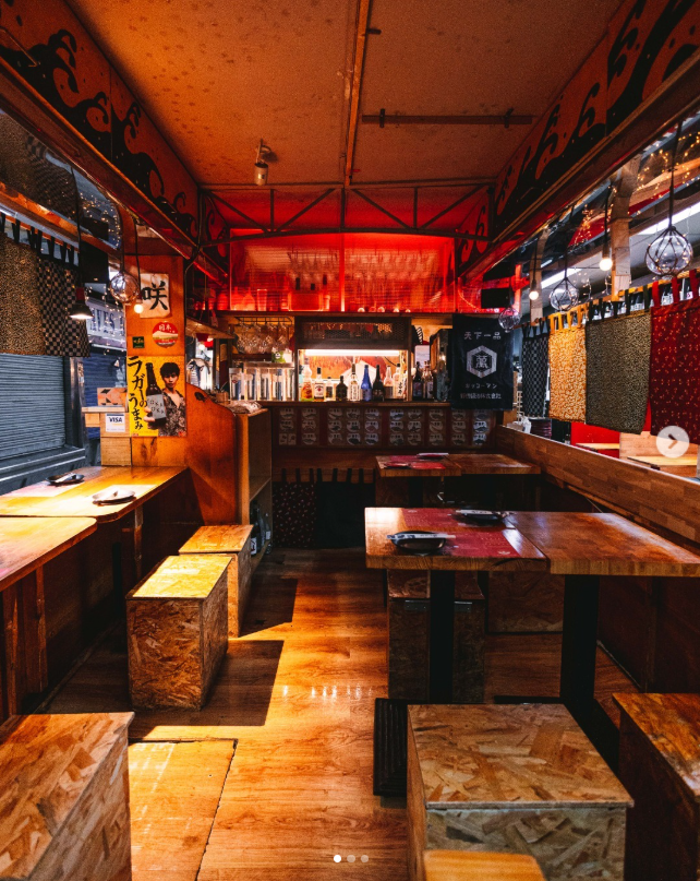 Interior del local en el Mercado Antón Martín con mesas de madera e iluminación cálida