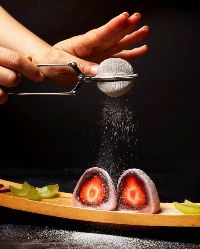 Mochi relleno de fresa espolvoreado con azúcar glas sobre una tabla de madera