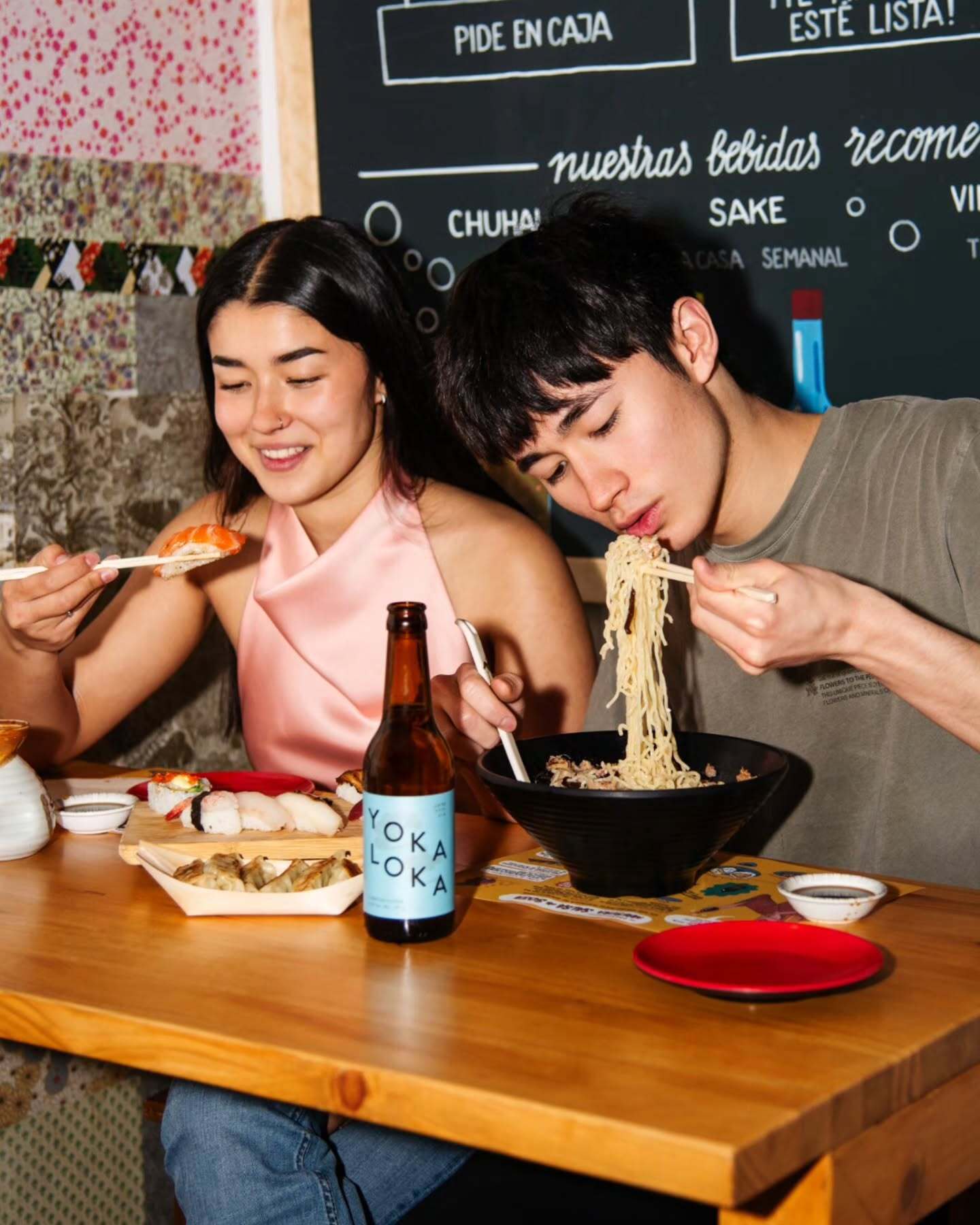 Dos comensales disfrutando sushi y ramen junto a una bebida de la casa YOKA LOKA
